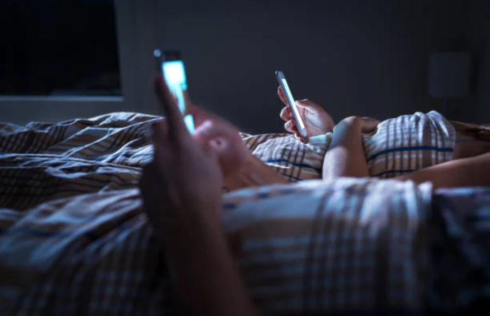 Un couple distant regardant chacun son téléphone au lit